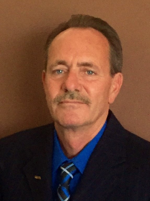 A person wearing a suit and tie smiling at the camera Description generated with very high confidence